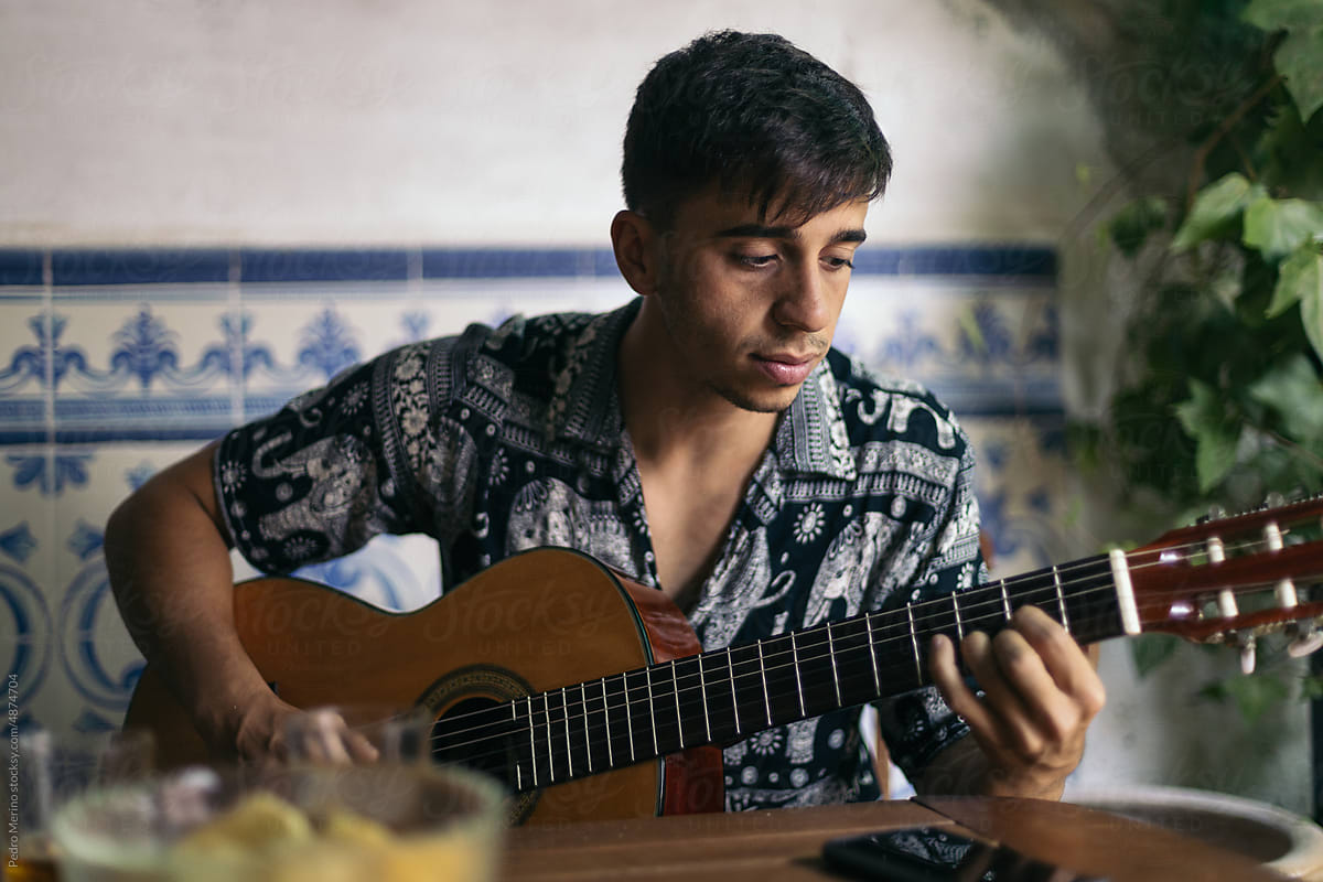 Young man playing the Spanish guitar in an outdoor patio