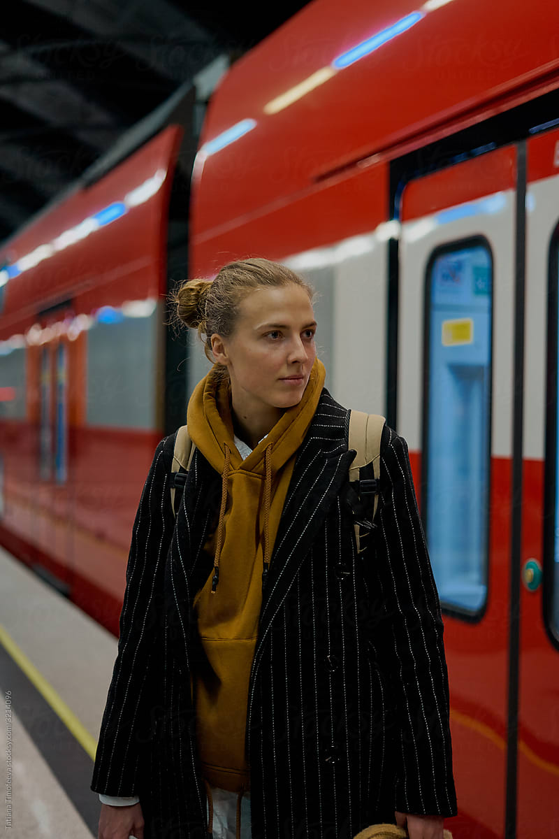 a woman traveler with a backpack is waiting red train