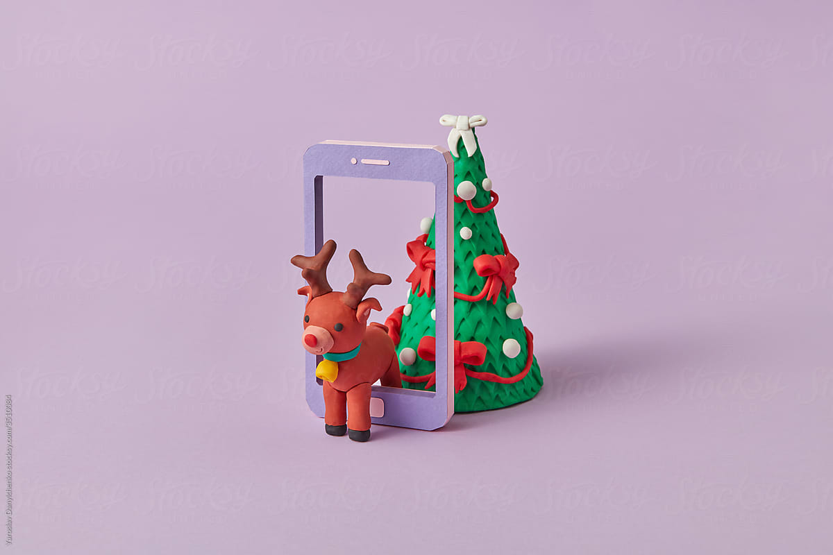 Plasticine figures of deer and fir in a tablet frame.