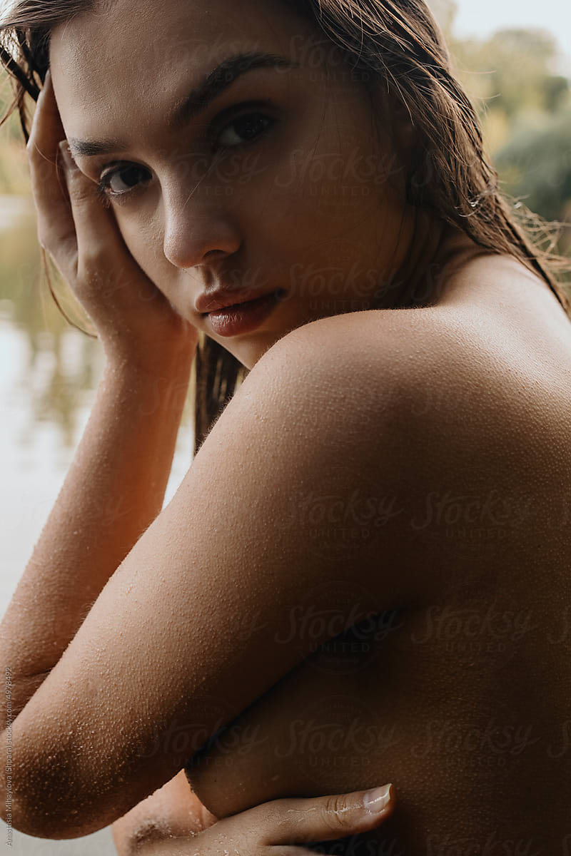 Portrait of naked woman with big eyes and brown hair in water
