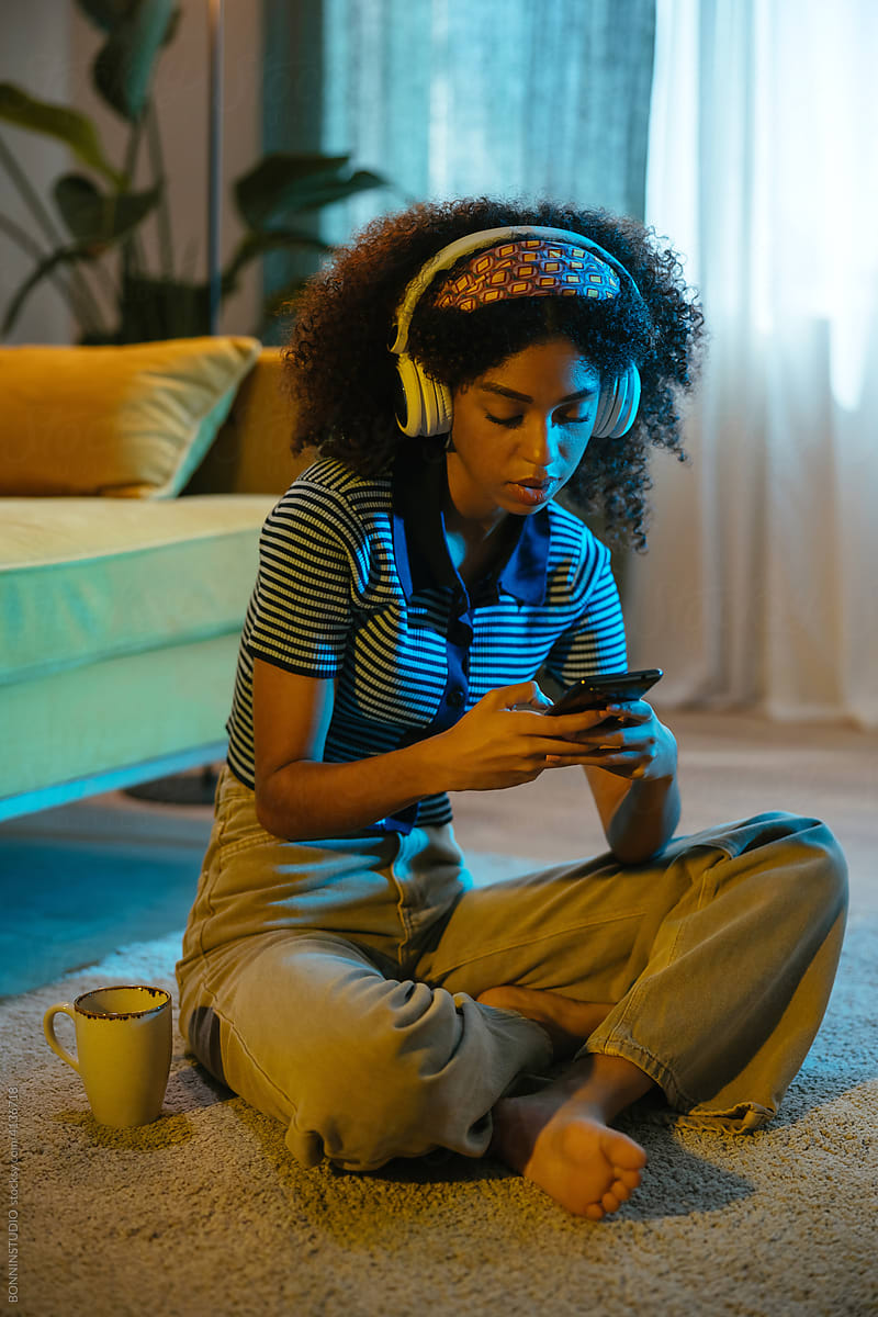 Black woman in headphones using smartphone at home