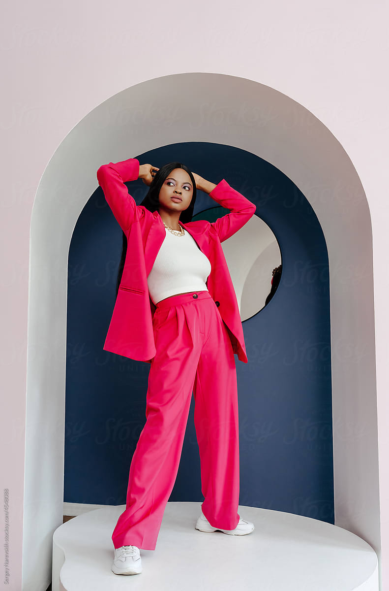 Fashionable woman in pink outfit in studio