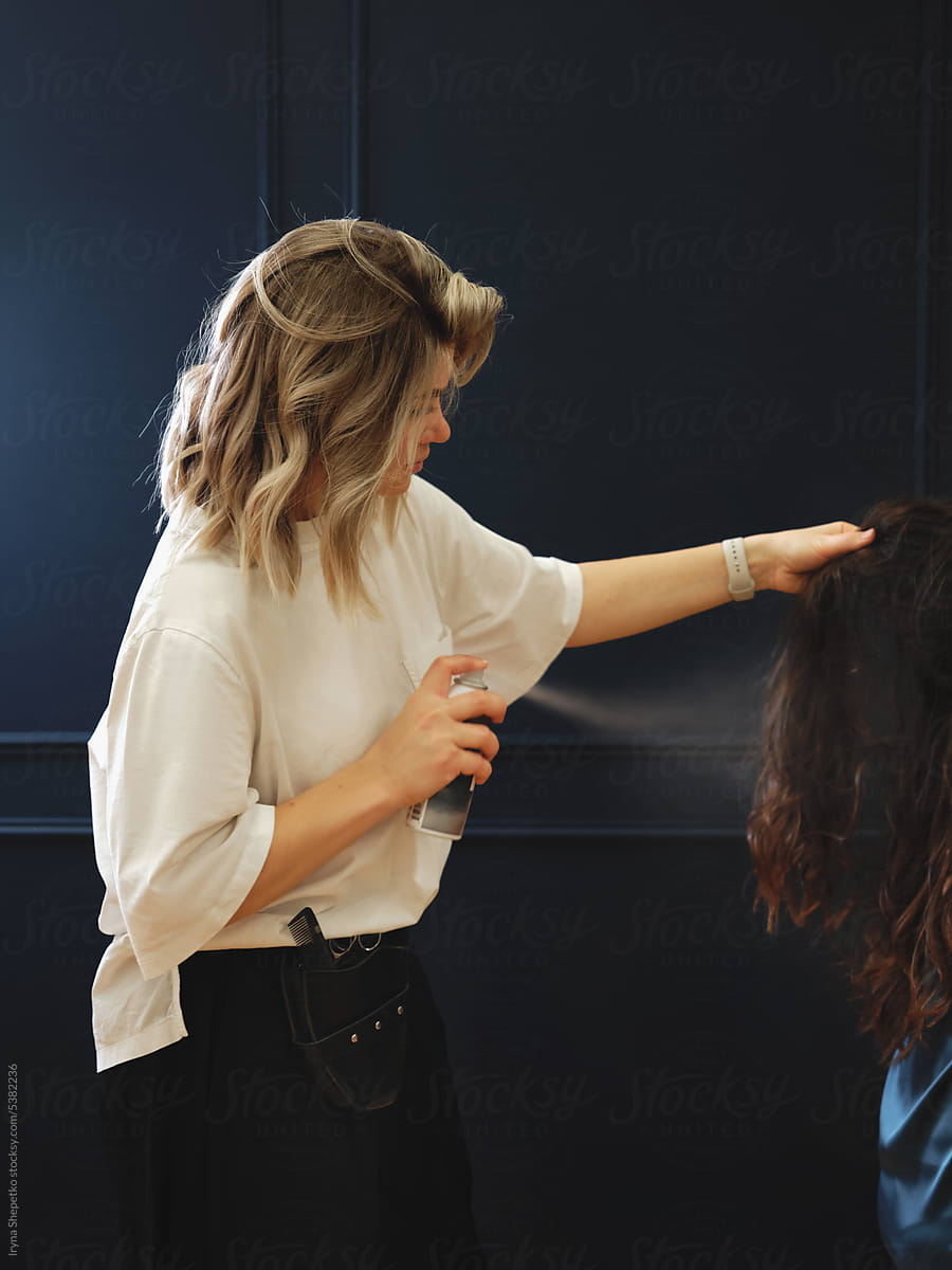 Young woman hair stylist spraying hairspray