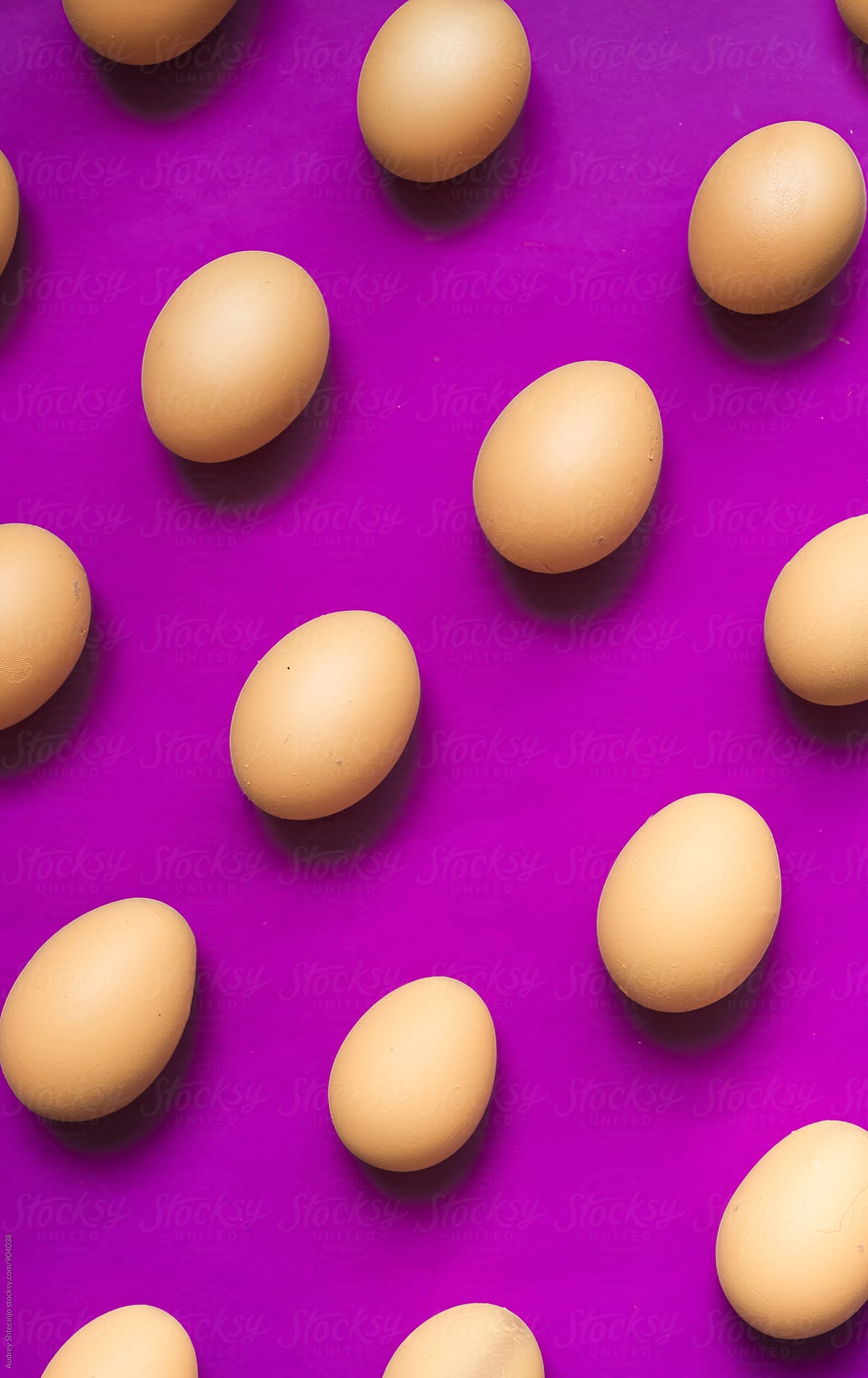 Well arranged raw/hardboiled eggs on purple background.