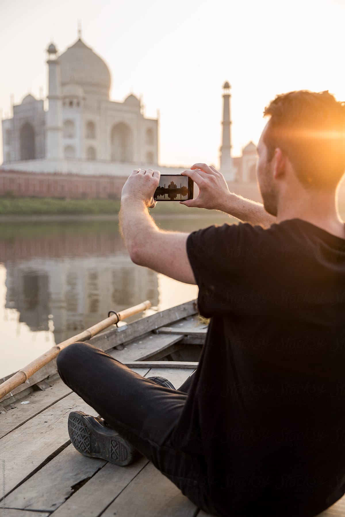 Tourist taking picture of Taj Mahal from boat