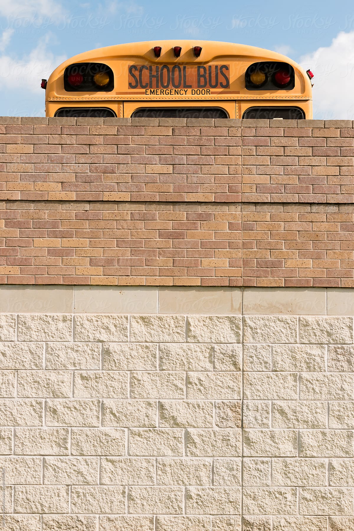 Yellow School Bus Peeking over a Brick Wall