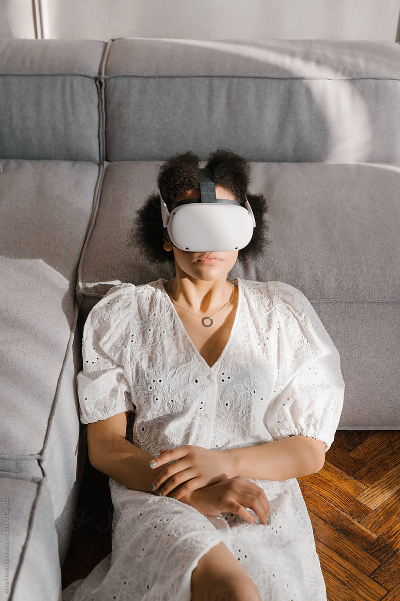 Black female in VR headset leaning on sofa