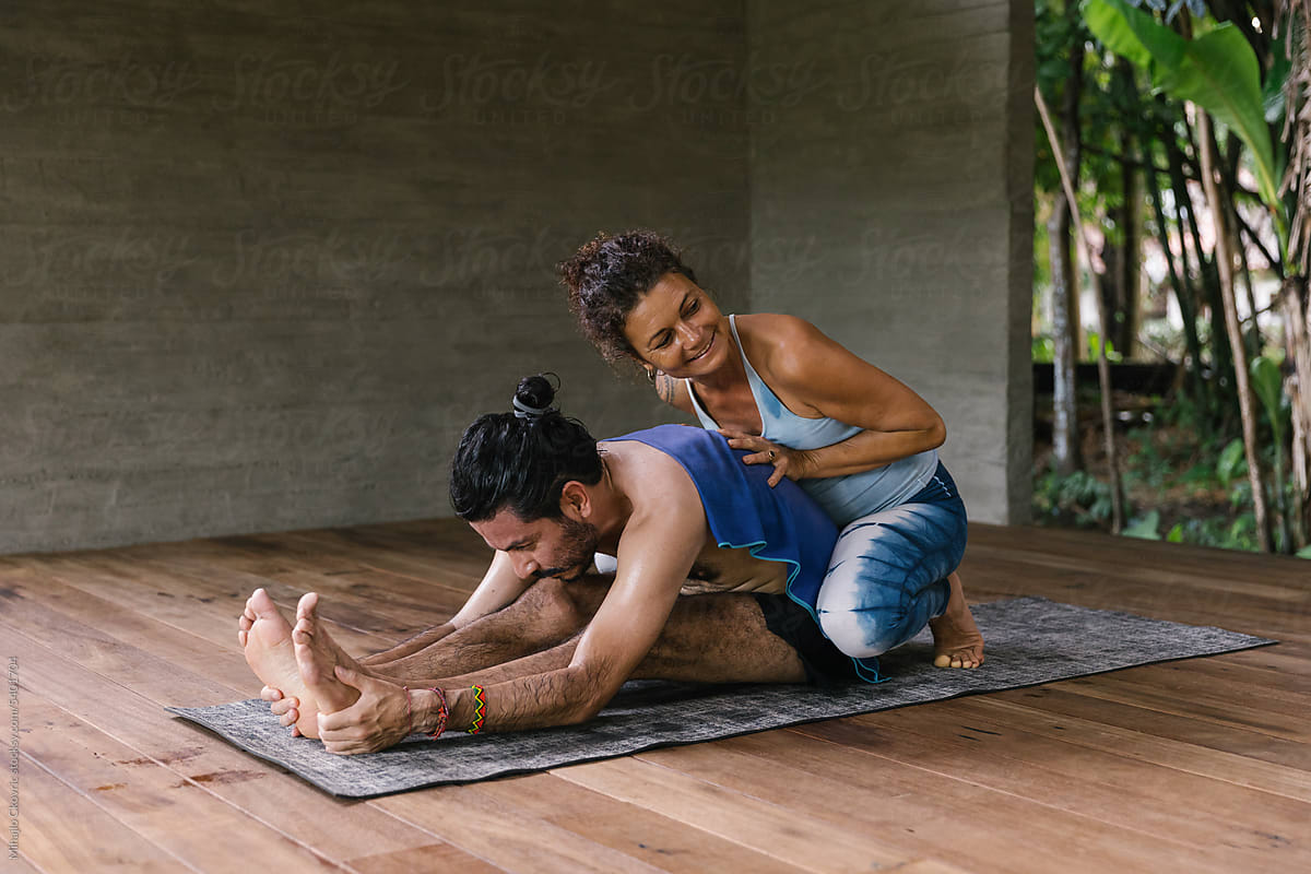 Female yoga teacher working with her male student