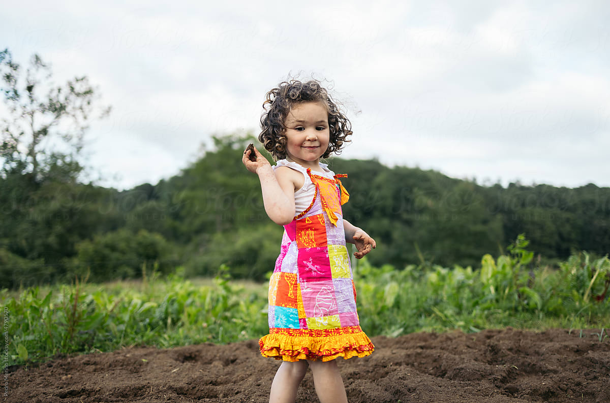 Little girl playing with the dirt on a farm
