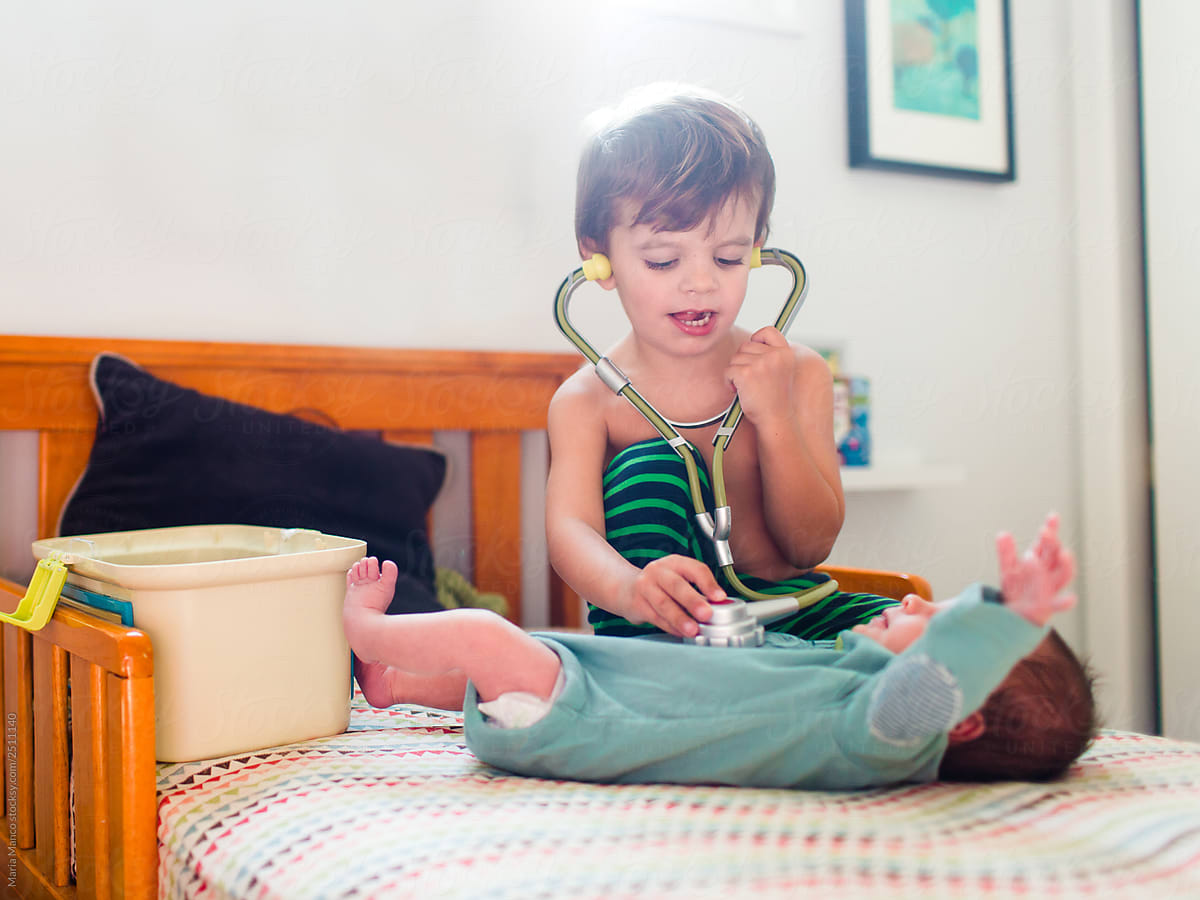 brother checks baby heartbeat with toy stethoscope
