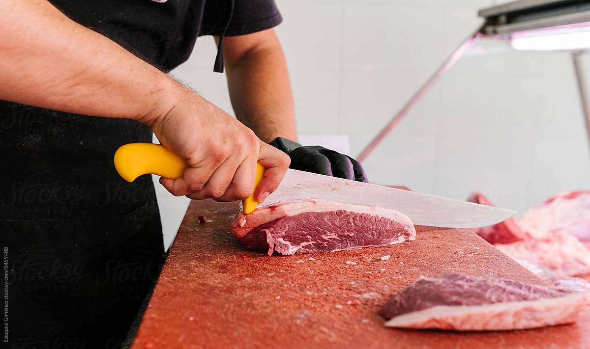Crop worker cutting pieces of meat in butchery