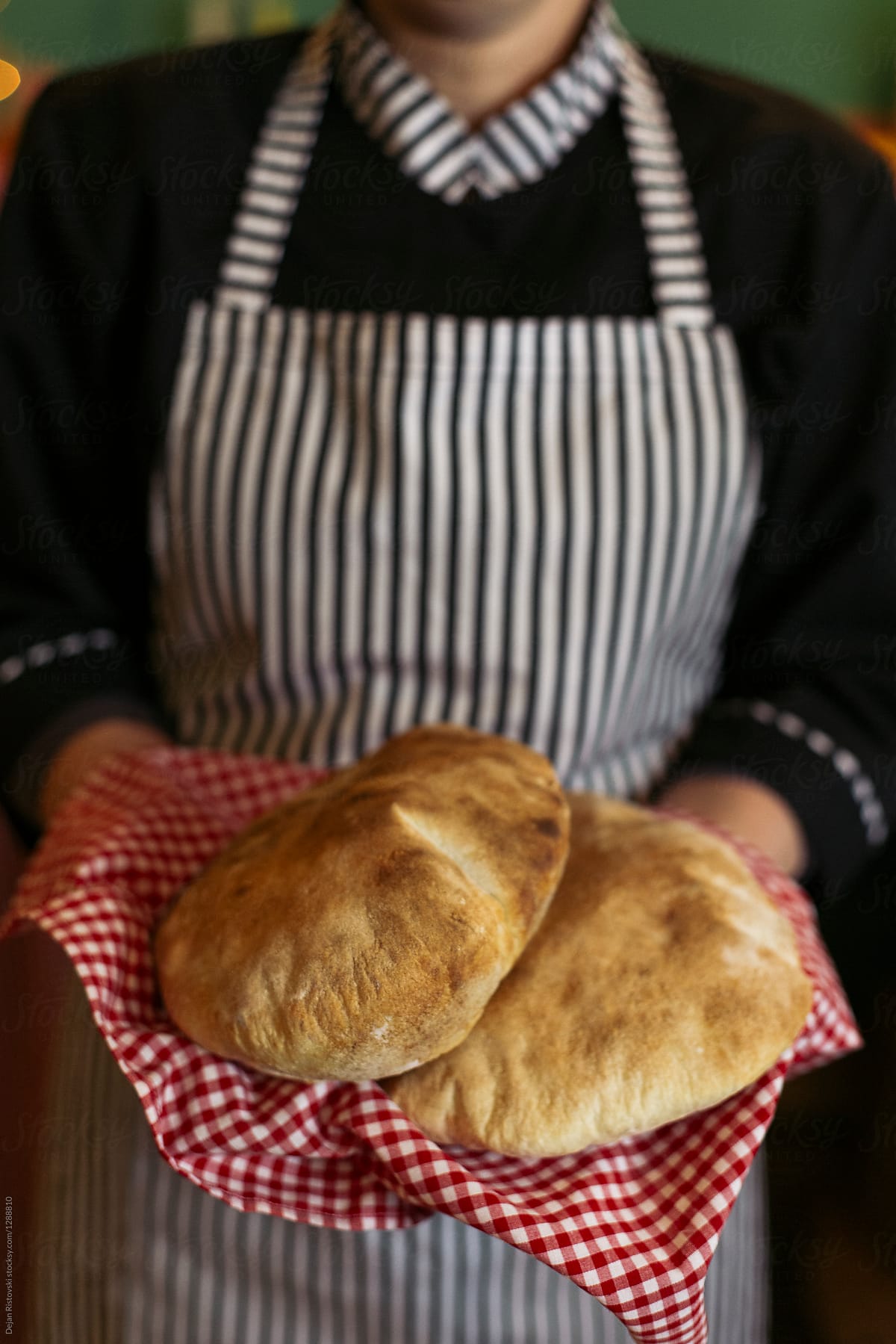 Baker holding fresh baked bread.