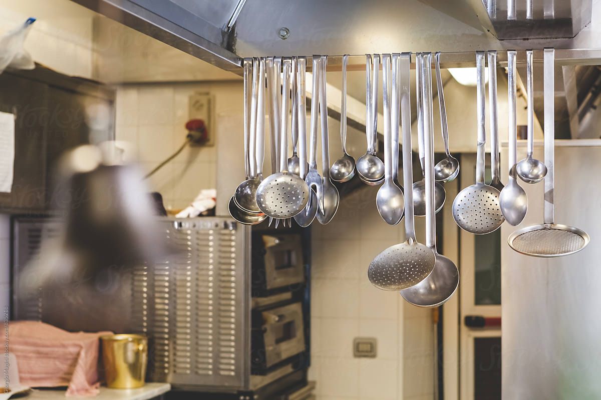 Many Cooking Utensils Hanging In A Professional Kitchen by Stocksy  Contributor Giorgio Magini - Stocksy