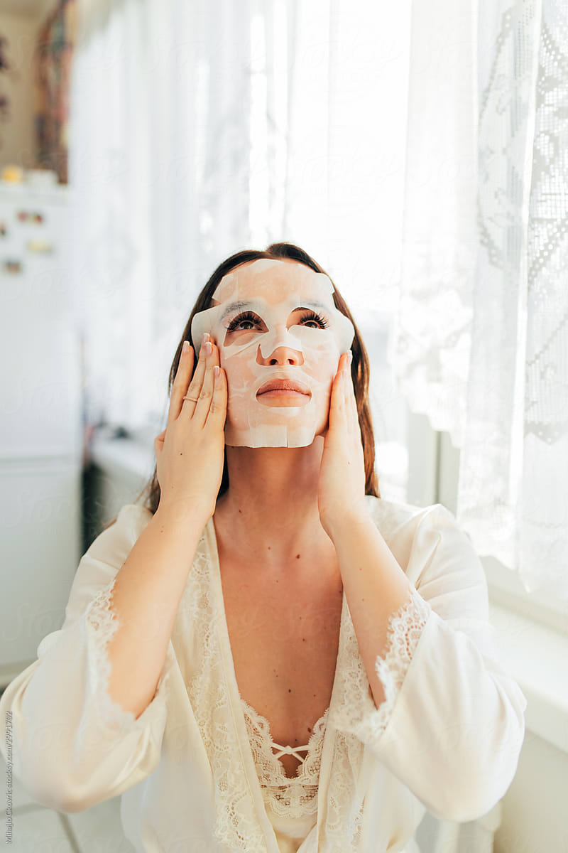 Young woman with a sheet moisturising mask on her face