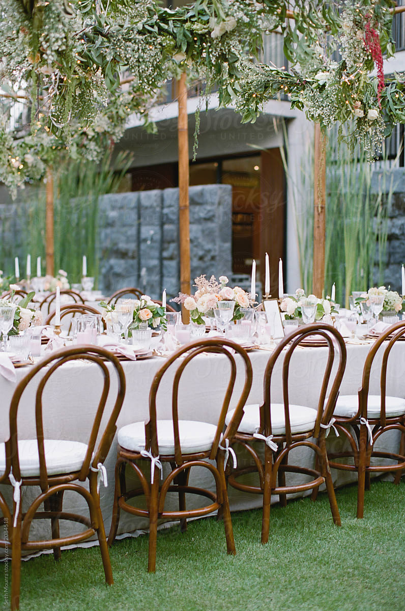 Outdoor, tropical wedding reception table with hanging greenery garlands