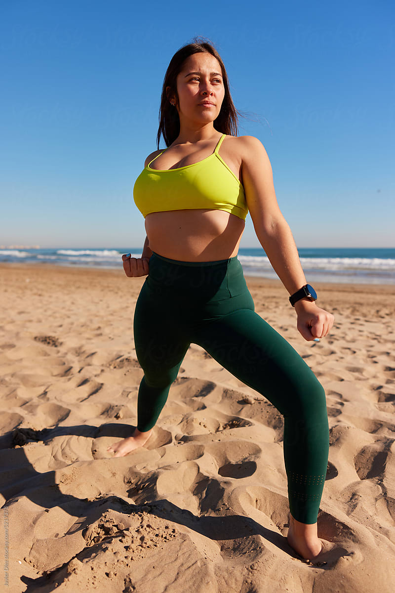 Sportswoman standing in fighting stance on beach