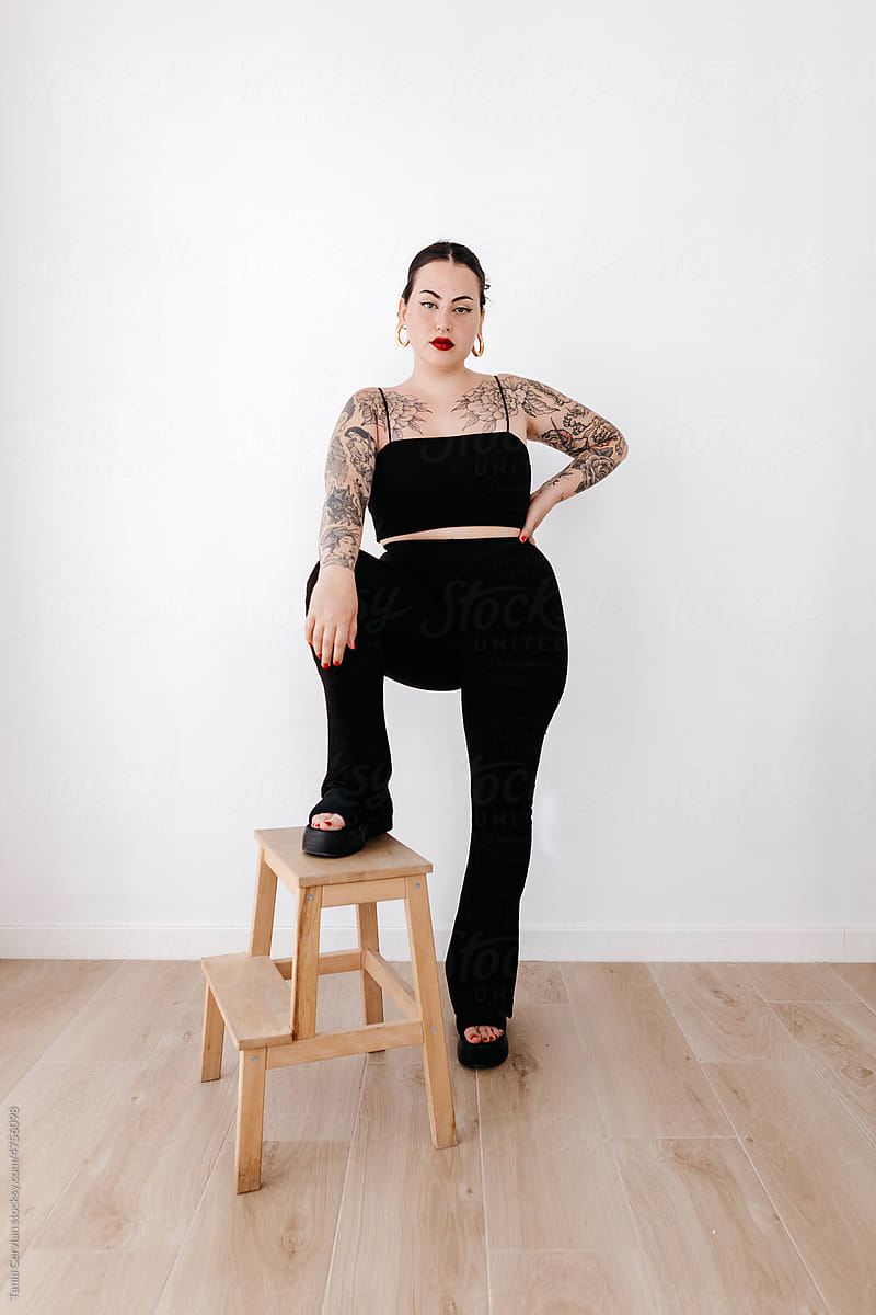 Confident tattooed woman standing on ladder