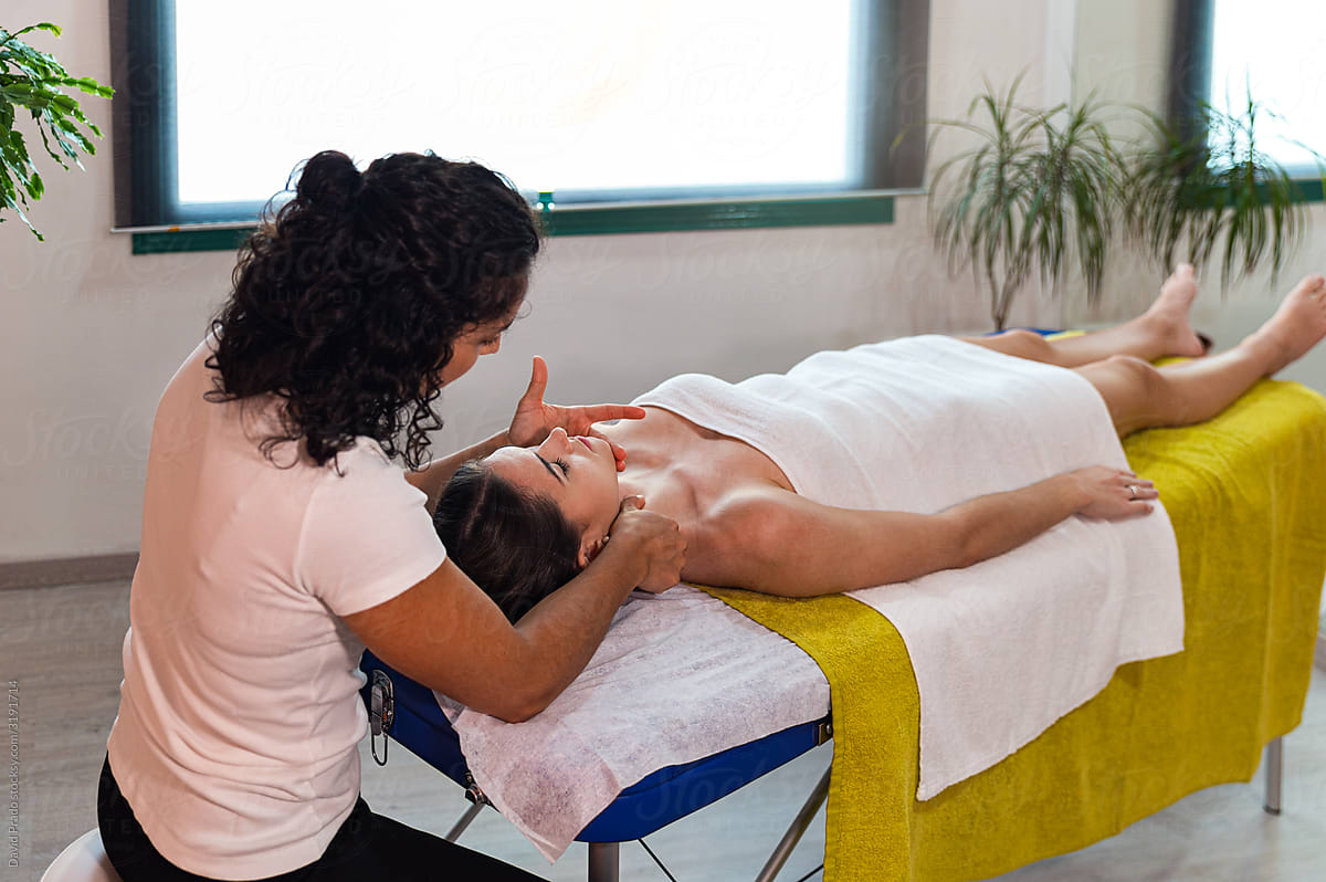 Masseuse treating female patient in light room