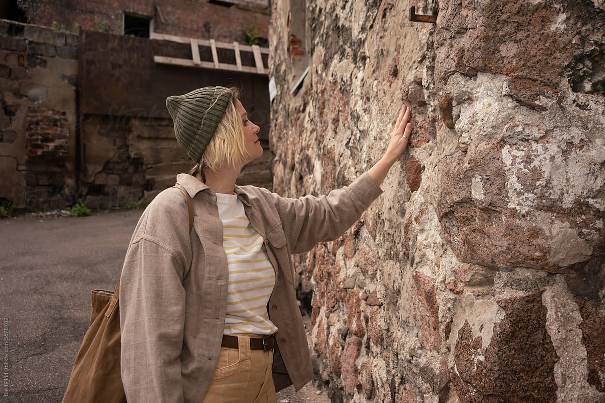 woman tourist touching old building wall