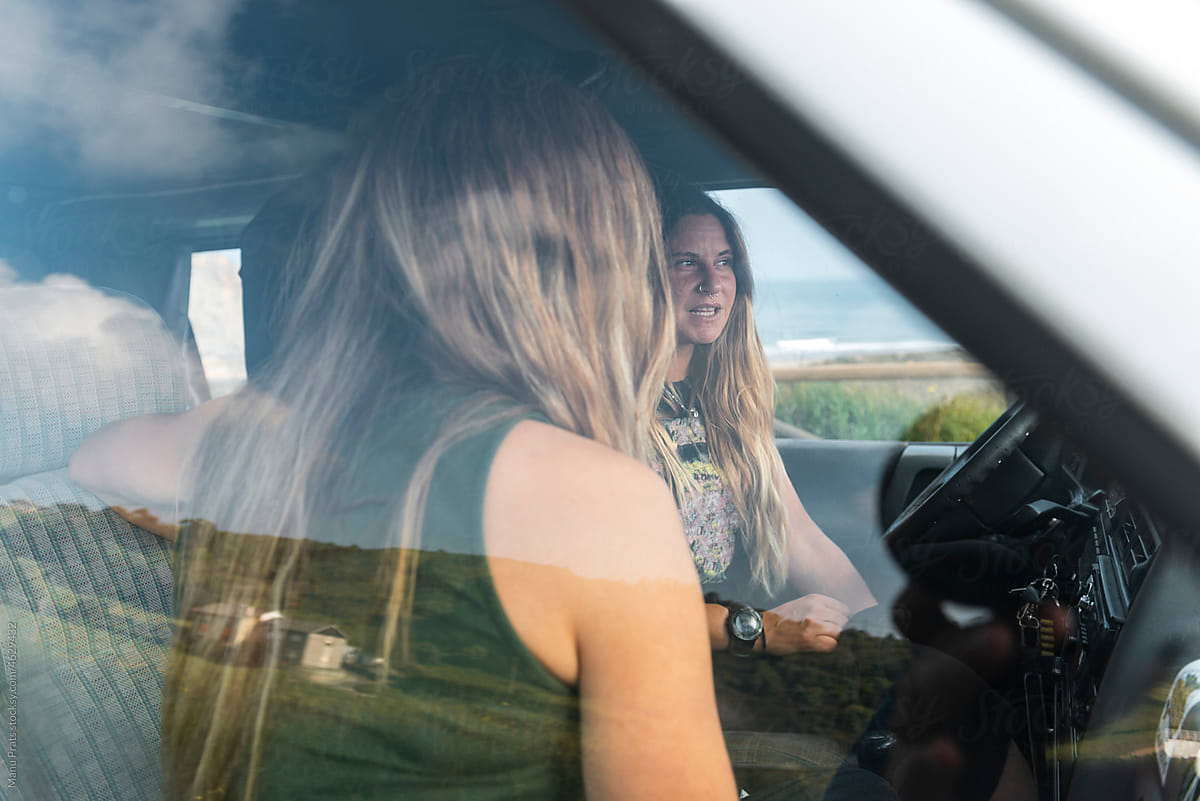 Millennial women driving camper van during surf trip