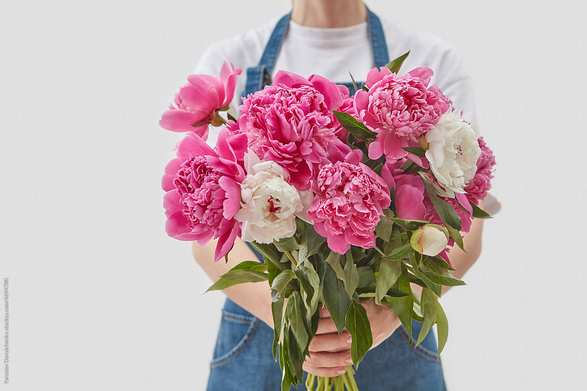 Woman holding bunch of pink peonies.
