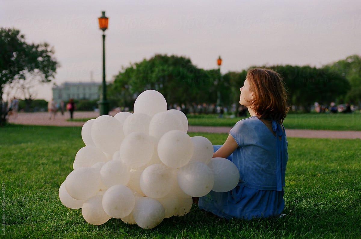 Young Woman Sitting On Grass With White Balloons Del Colaborador De Stocksy Amor Burakova 