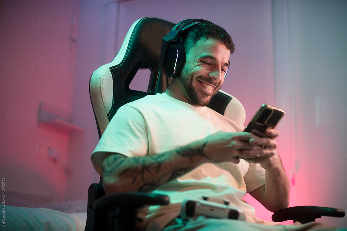 Happy gamer using mobile phone with headset