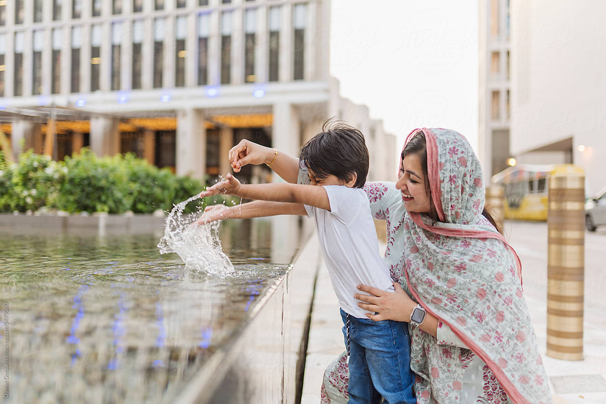 Boy with mother playing with fountain water