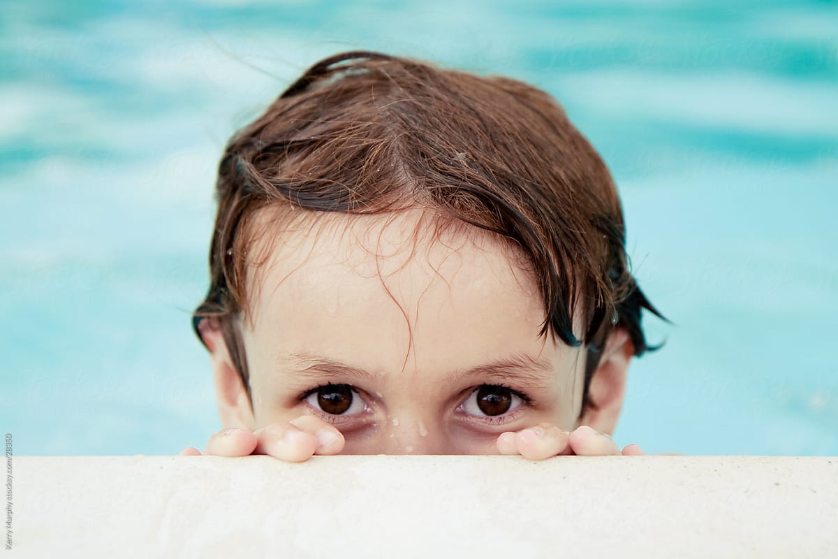 Boy peeking over edge of swimming pool