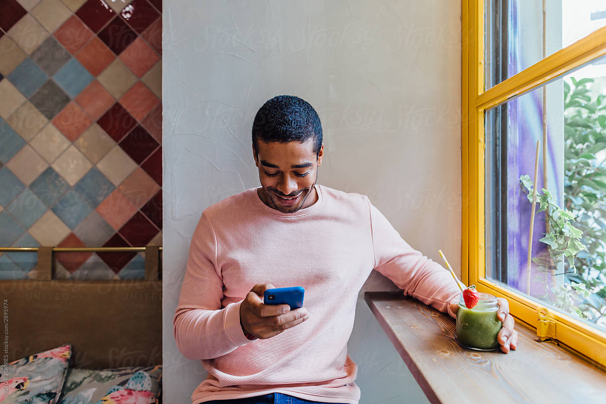 Happy man using phone in cafe