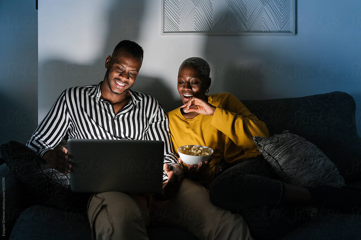 Black couple watching interesting movie at night