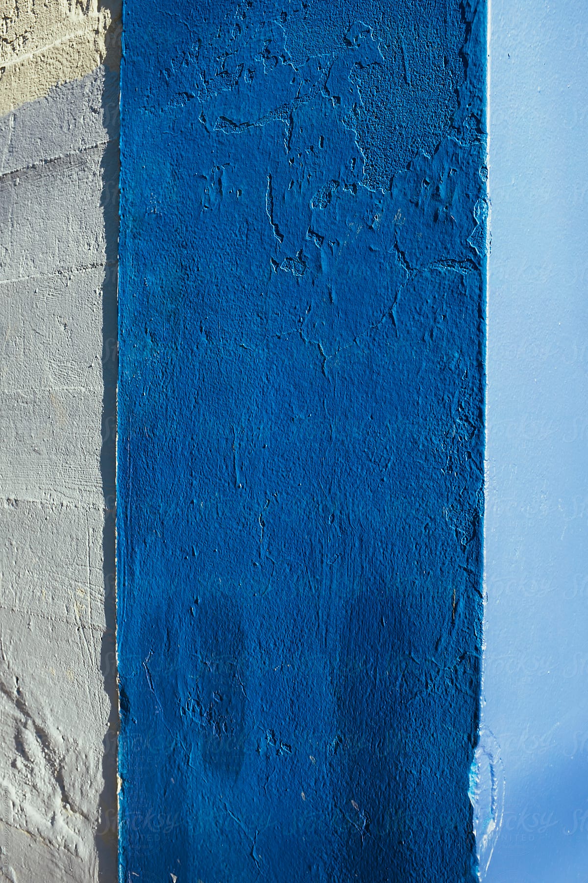 Corner of building wall exterior, painted different shades of blue and casting shadow