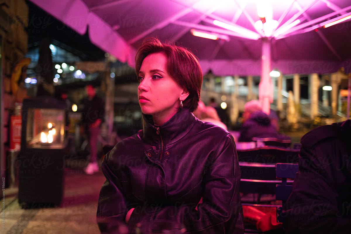 Bored woman at outdoor café with pink lighting