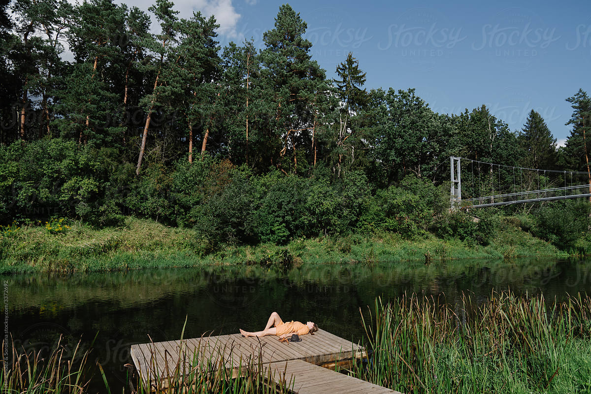 Woman Enjoying Nature Laying On The Footbridge