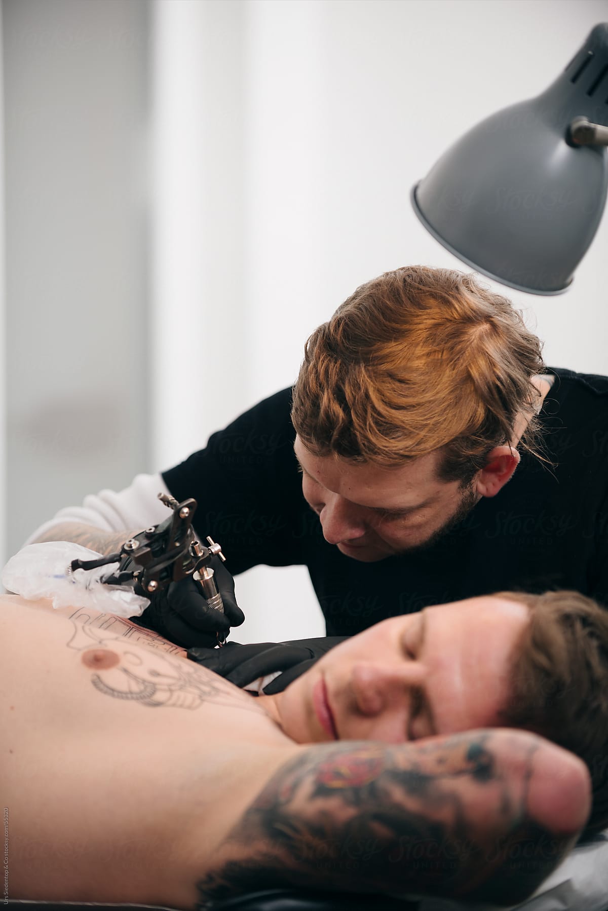 Tattoo artist tattooing man\'s chest