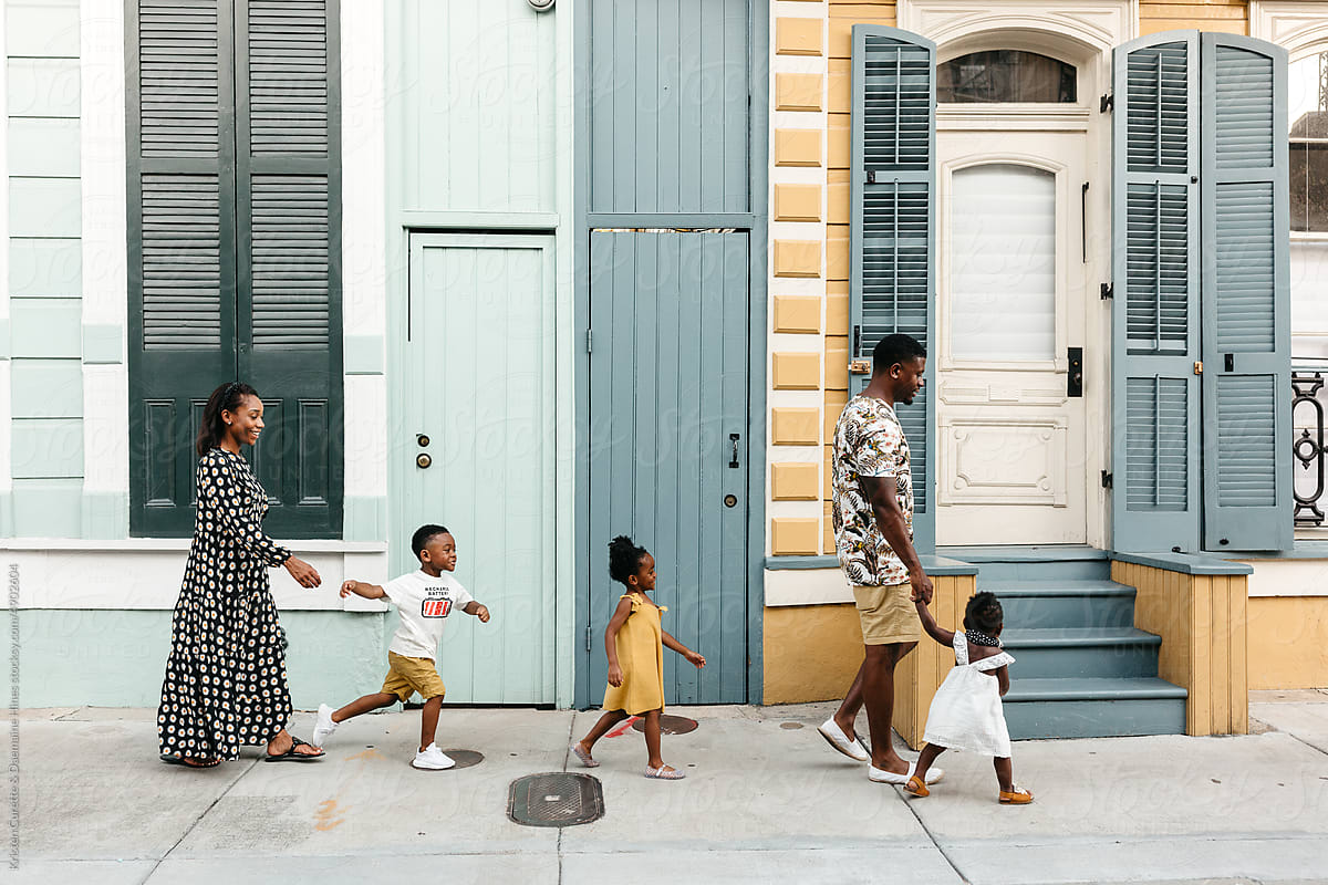A beautiful African American family walking down a sidewalk by Kristen Curette & Daemaine Hines for Stocksy United