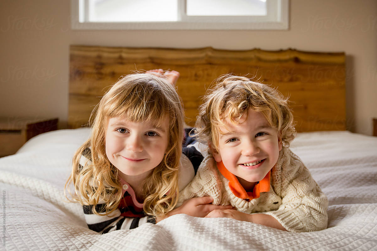 Cute siblings lay on bed and smile for camera