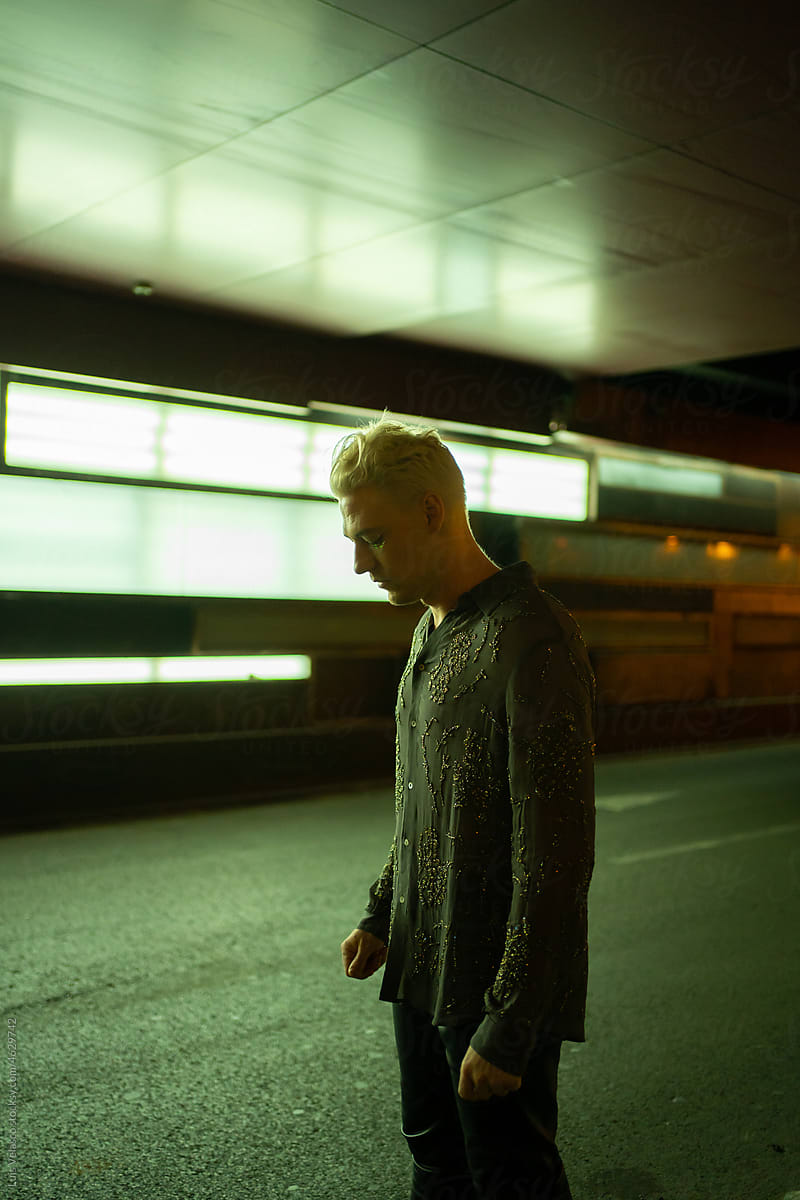 Worried And Depressed Blonde Man Standing Outdoors At Night.