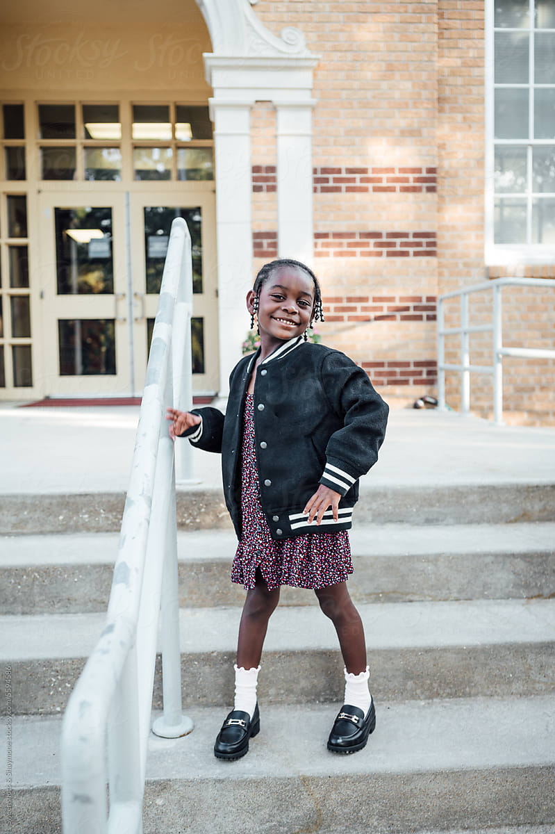 Little girl standing on steps smiling for the first day of school