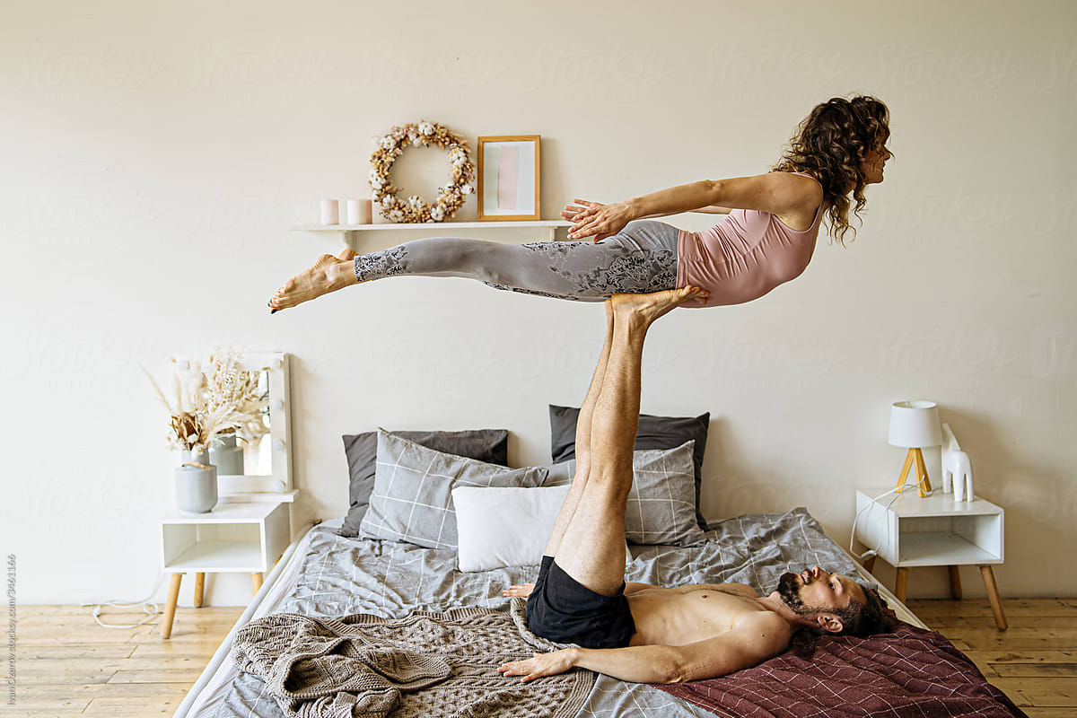 couple doing acro yoga in bed
