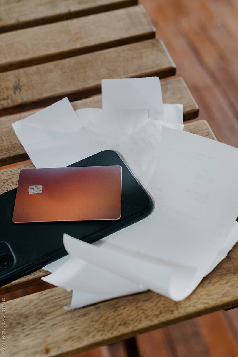 Bunch or receipts on the table with card and smartphone