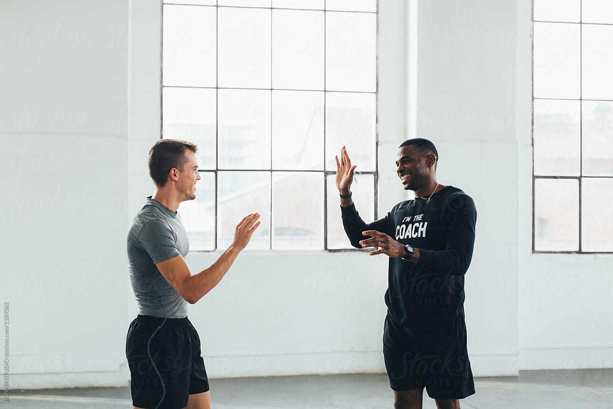 Fit man giving high five with his coach in the gym.