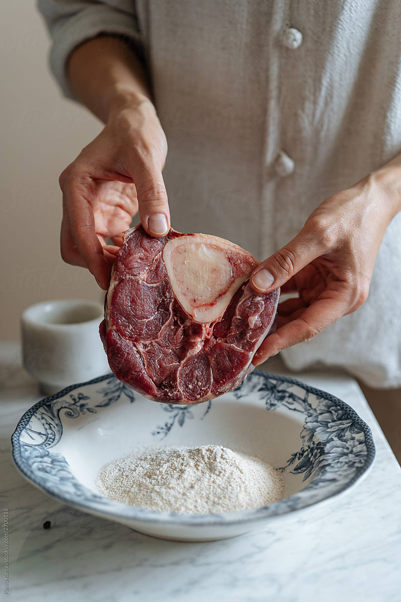 Faceless chef placing steak in dish of flour