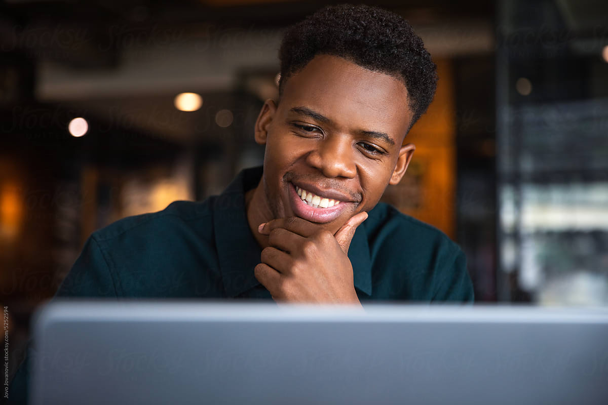 Smiling man using laptop with his hand on chin