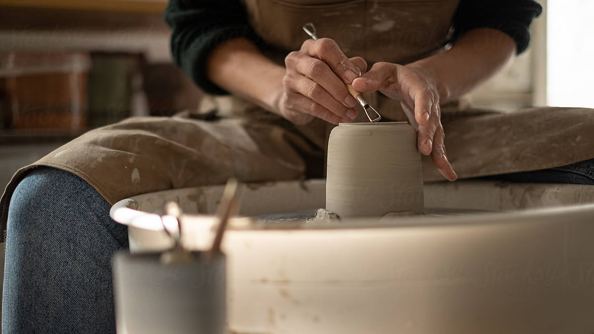 Faceless artisan molding a vase with a lathe