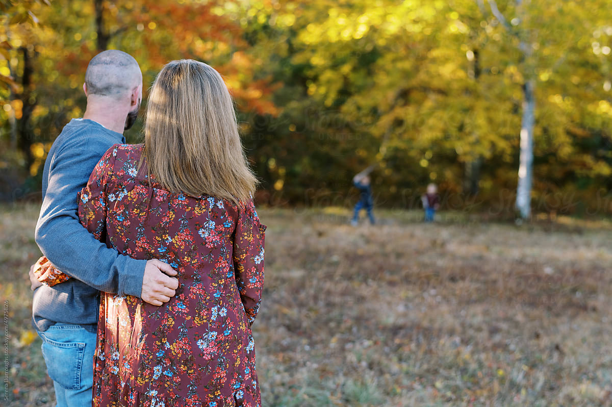 Couple looking at their children playing outdoors in autumn