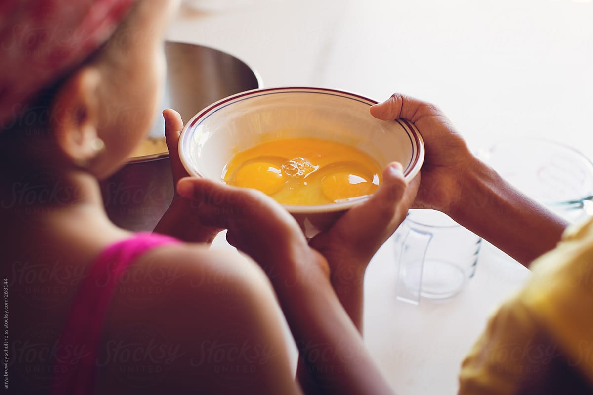 Two young children holding a bowl  of shelled eggs