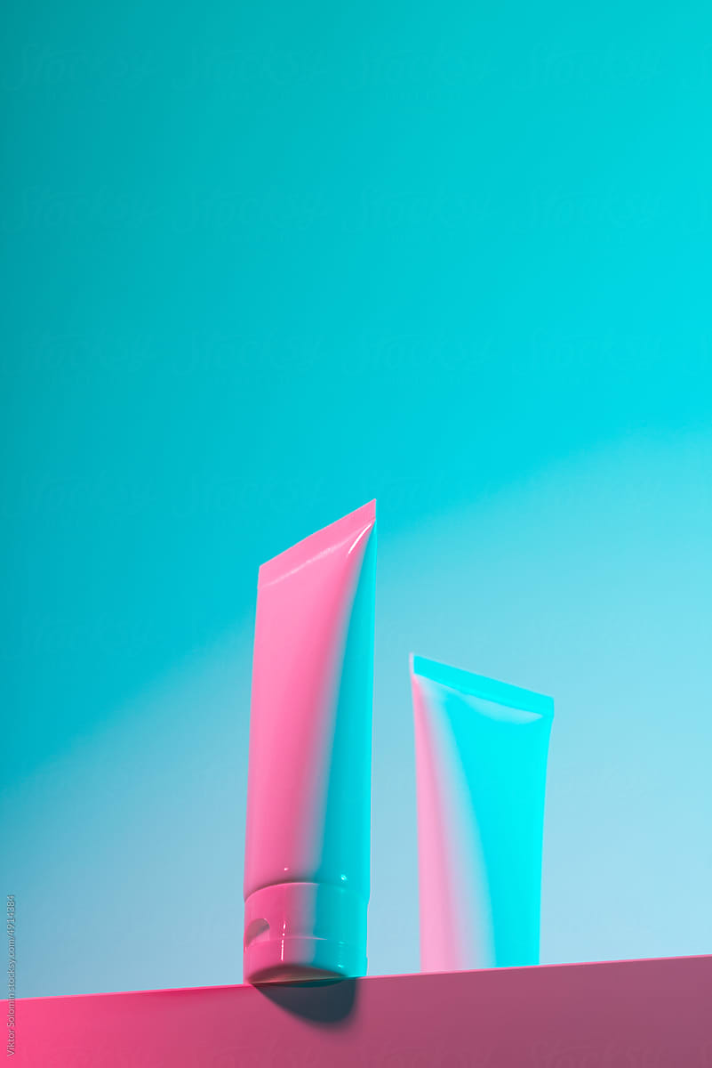 Set of pink and blue hand-cream tubes on pink background in studio