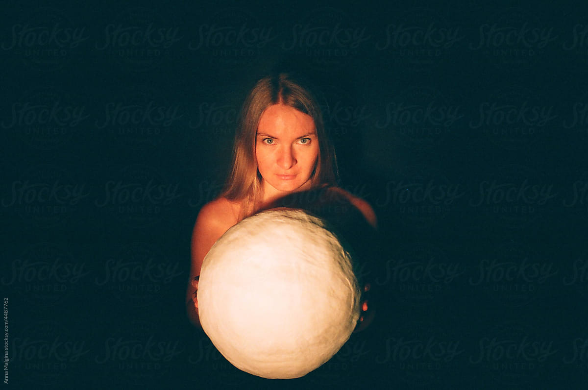 a woman with a white paper moon looking at camera