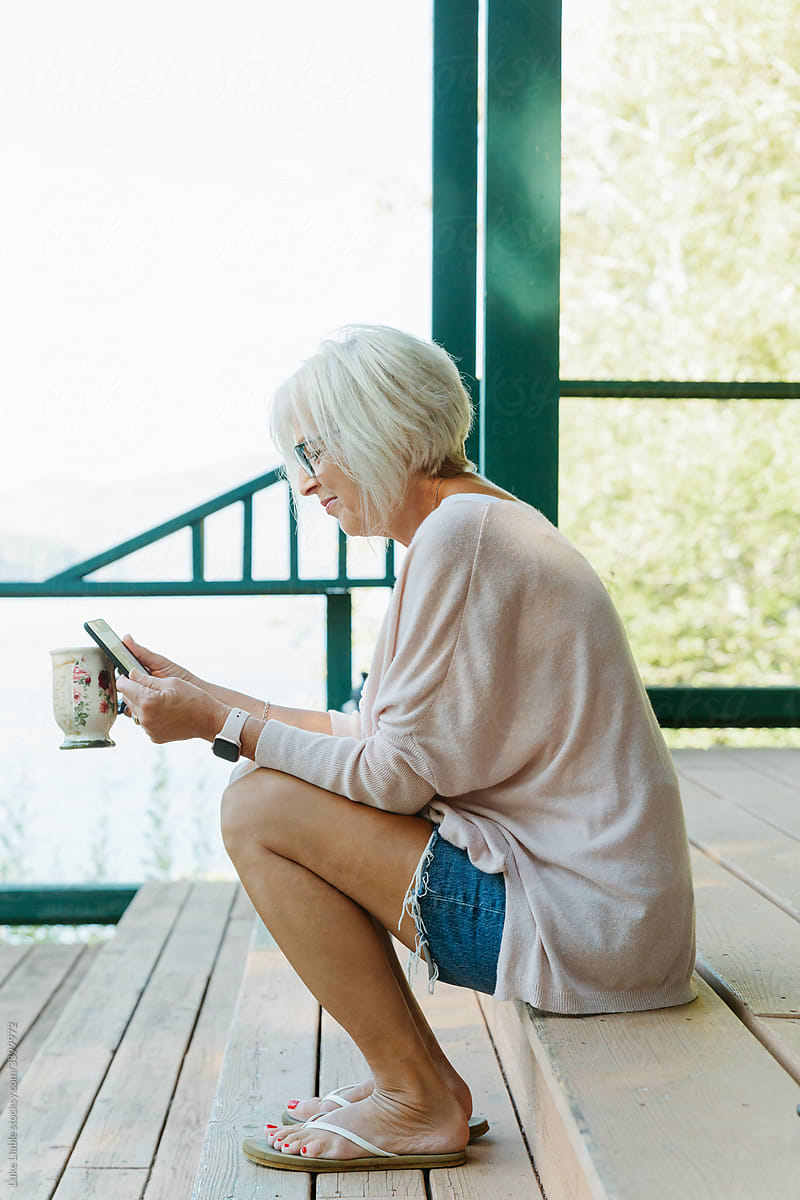Happy elderly woman drinking coffee on deck